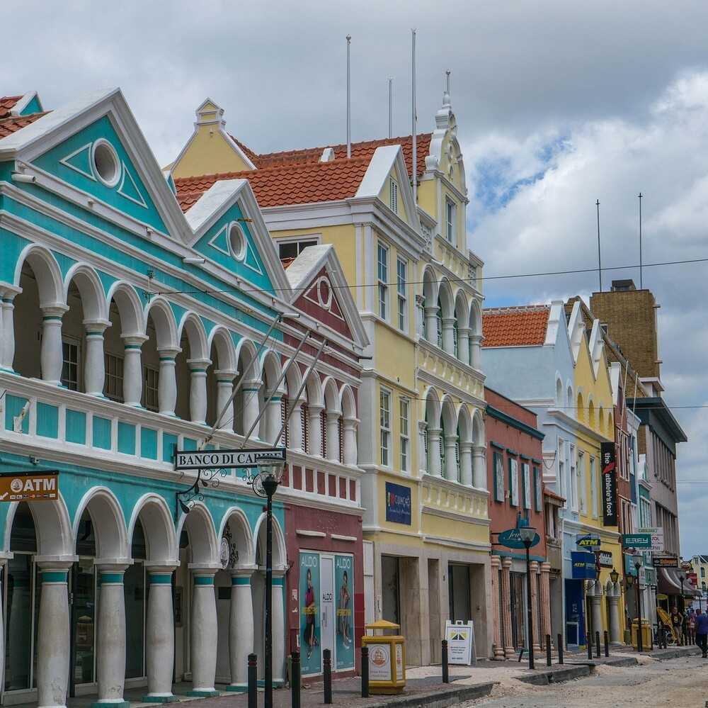 Willemstad, Curaçao's capital city, began as Dutch colonial trading and administrative settlement in 1634, with the construction of Fort Amsterdam on Sint Anna Bay. The red, blue, yellow ochre, and green on Willemstad buildings date from 1817, when the previous white-lime finish was prohibited to protect eyesight from the glare.