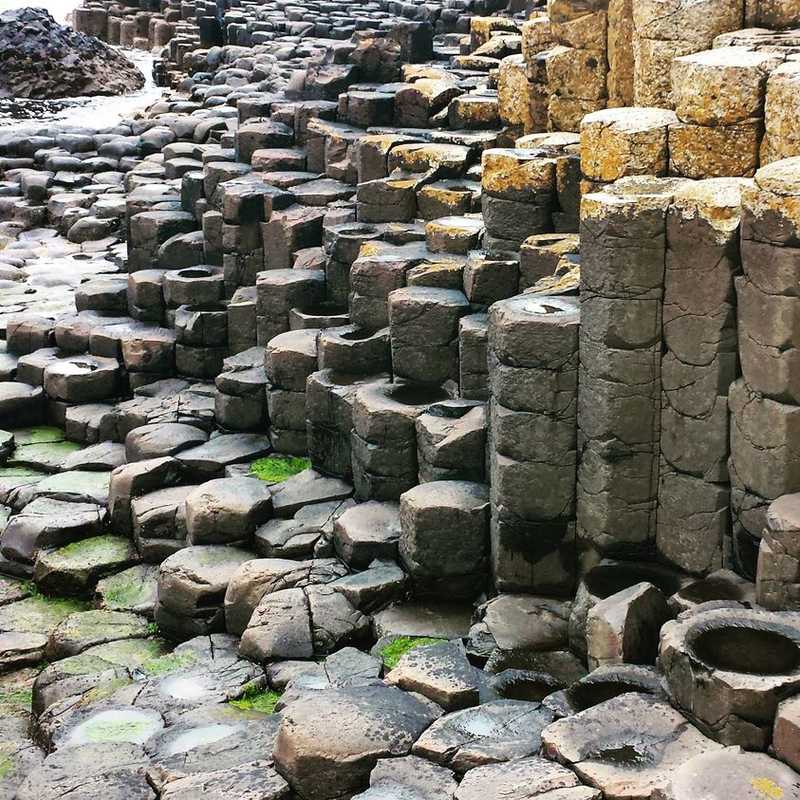 A closeup of basalt columns that make up the Giant's Causeway in Northern Irelenad. The Causeway is a site of about 40,000 interlocking basalt columns, the result of an ancient volcanic eruption. As the lava cooled, contraction occurred in a pattern similar to that of drying mud, with the cracks propagating in a generally hexagonal pattern and downward, leaving pillarlike structures. The unique geological formation is located in County Antrim on the north coast of Northern Ireland, about 5 km (3 mi) northeast of the town of Bushmills.