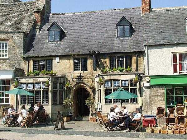 Relaxing outside a restaurant in the town of Burford, the Cotswold hills district, England.