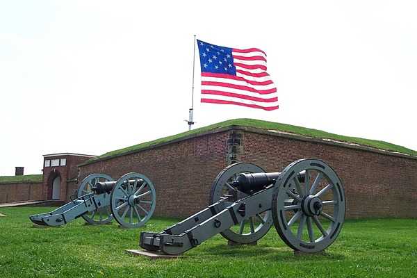 Two field pieces in front of Fort McHenry in Baltimore, Maryland with the garrison flag flying in the background. Photo courtesy of the National Park Service.