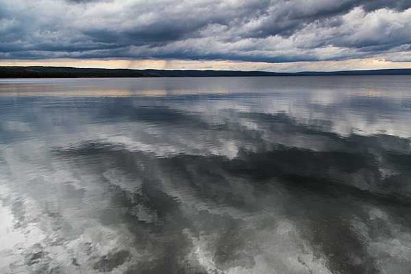 Gray clouds reflected over a calm Yellowstone Lake. Image courtesy of the US National Park Service/Neal Herbert.