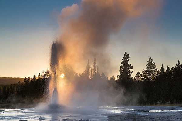 The setting sun shines through an eruption of Pink Cone Geyser in Yellowstone National Park. Image courtesy of the US National Park Service/Neal Herbert.